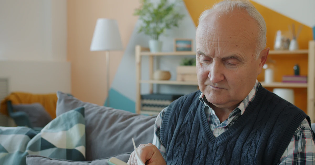 Älterer Mann, der auf einer Couch ein Buch liest