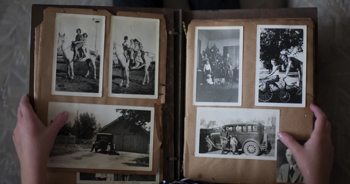 Person, die ein Fotoalbum mit Graustufenfotos öffnet