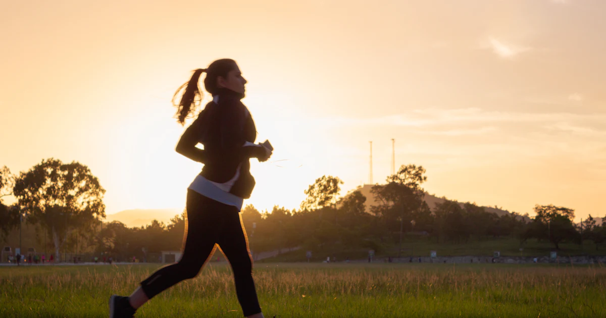 Eine Frau in Silhouette, die während der goldenen Stunde auf einem Weg läuft