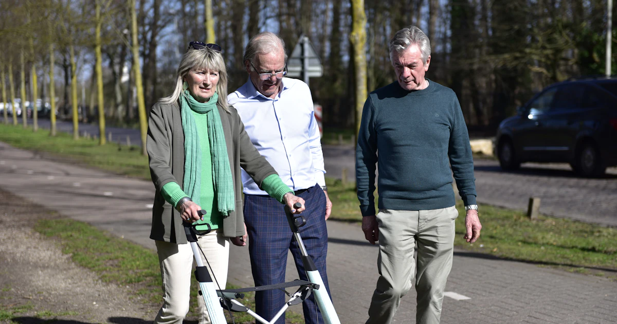 Drei Personen mit einem Rollator auf einem Weg