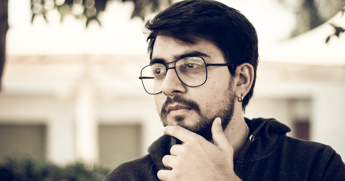 Mann in schwarz gerahmter Brille und blauem Pullover