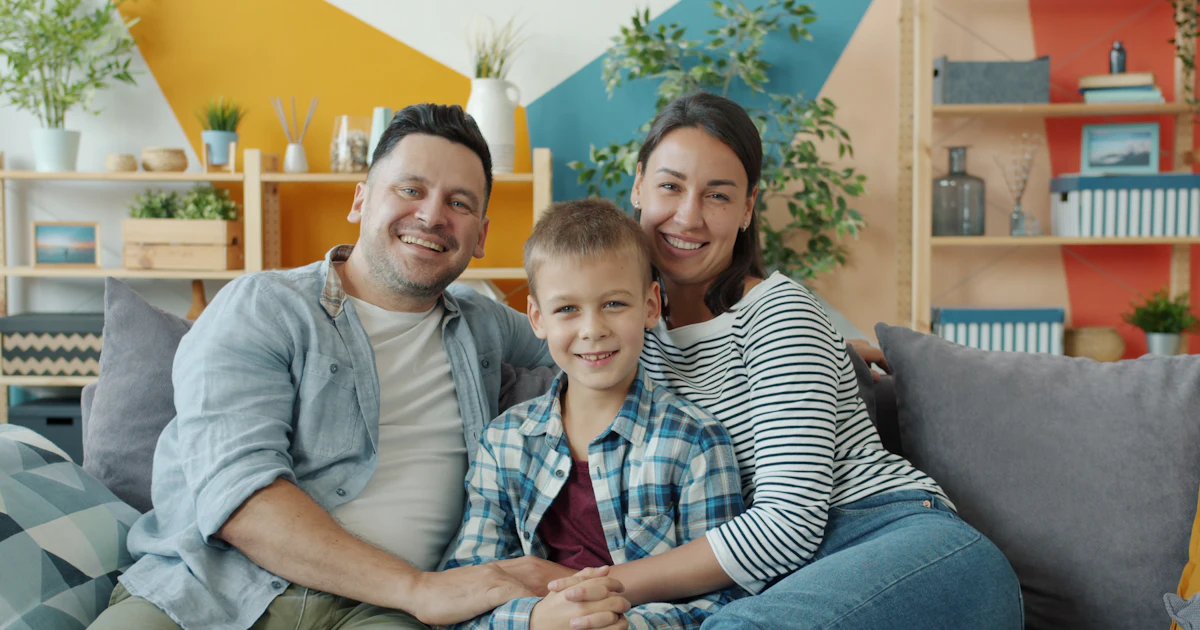 Eine glückliche dreiköpfige Familie, die auf einer Couch sitzt